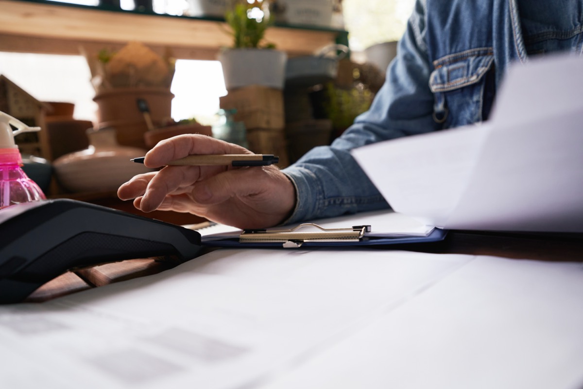 Hands working through a stack of invoices on a shop counter
