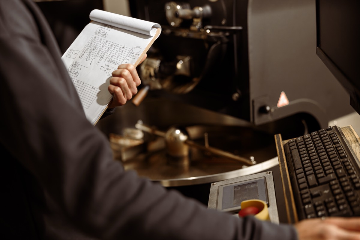 A paper run sheet held up beside a machine and a keyboard